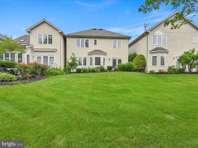 a view of a white house with a big yard and large trees