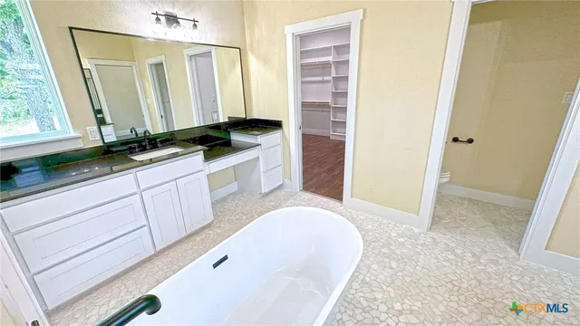 a spacious bathroom with a bathtub sink and mirror