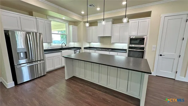 a kitchen with granite countertop a sink a window stainless steel appliances and cabinets