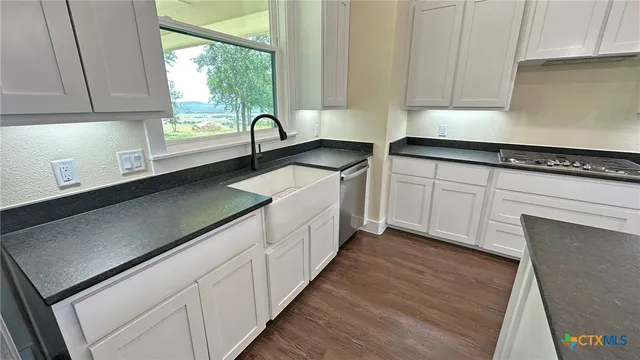 a kitchen with stainless steel appliances granite countertop a refrigerator a stove a sink and a microwave oven with wooden floor