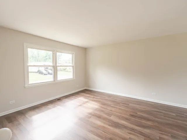 a view of a kitchen with wooden floor and a window