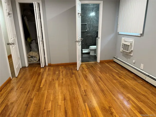 a view of an empty room with wooden floor and a bathroom