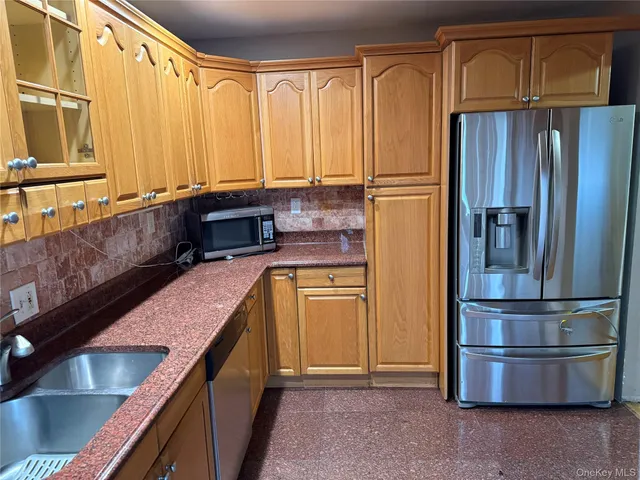 a kitchen with stainless steel appliances granite countertop a refrigerator a stove and a sink with wooden floors