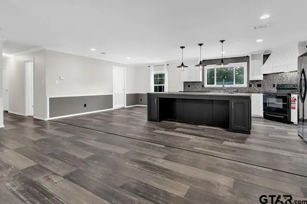 a kitchen with granite countertop kitchen island stainless steel appliances a sink stove and cabinets