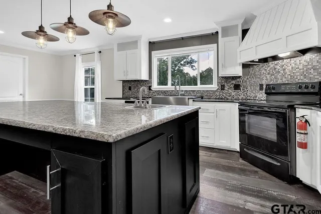 a kitchen with granite countertop a sink and a white wooden cabinets