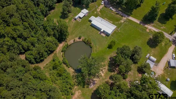 an aerial view of residential house with outdoor space and trees all around