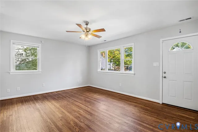 a view of empty room with wooden floor and fan