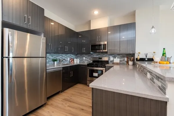 a kitchen with stainless steel appliances a refrigerator a sink a stove a microwave and wooden cabinets