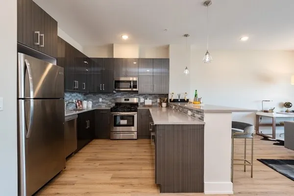 a kitchen with stainless steel appliances granite countertop a refrigerator a stove and a sink