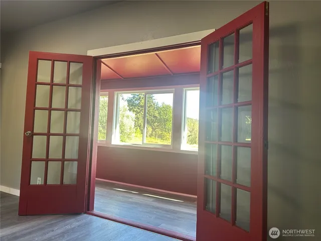 a view of an empty room with wooden floor and a window