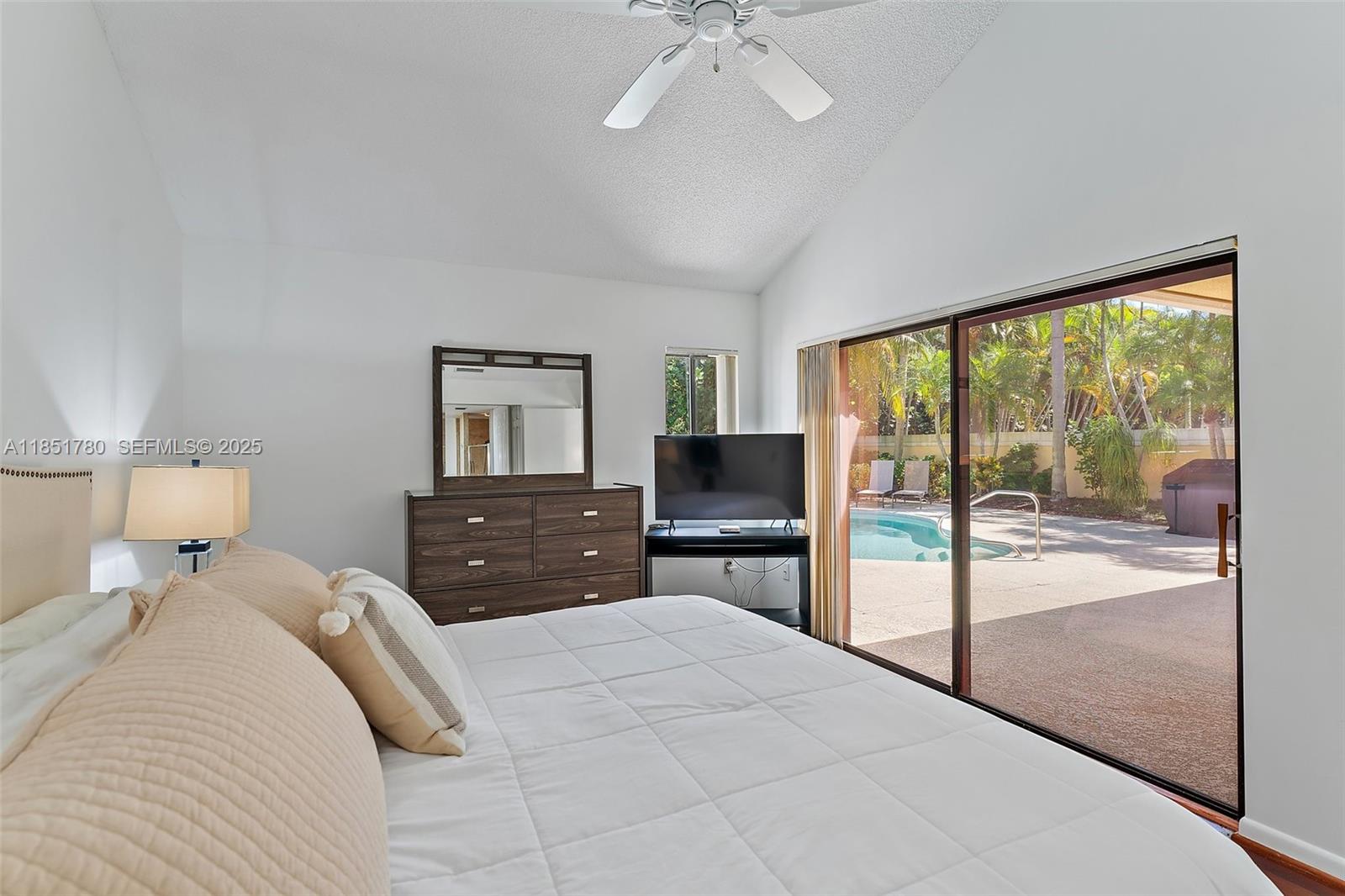 101 Sand Pine Drive, Unit 101 Jupiter, FL 33477 - Photo 15 of 33 a bedroom with a large bed and a flat tv screen on dresser