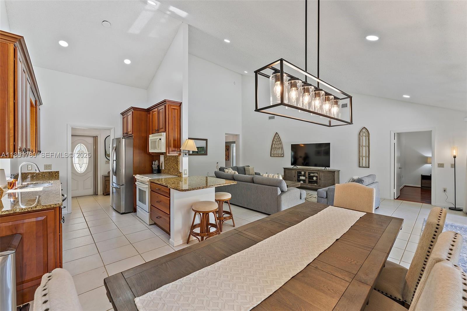 101 Sand Pine Drive, Unit 101 Jupiter, FL 33477 - Photo 9 of 33 a living room with furniture a flat screen tv and kitchen view