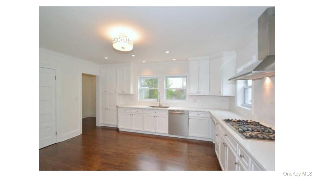2 Arleigh Road Great Neck, NY 11021 - Photo 8 of 22 Kitchen featuring white shaker cabinetry, stainless steel appliances, recessed lighting, and wood-finish flooring