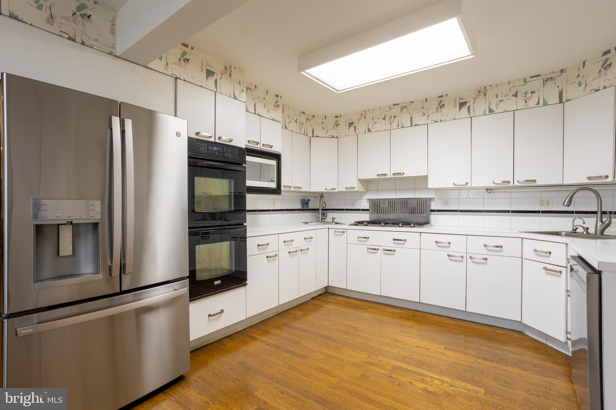 3215 Northbrook Road Baltimore, MD 21208 - Photo 10 of 50 a kitchen with granite countertop a refrigerator oven a sink dishwasher and white cabinets with wooden floor