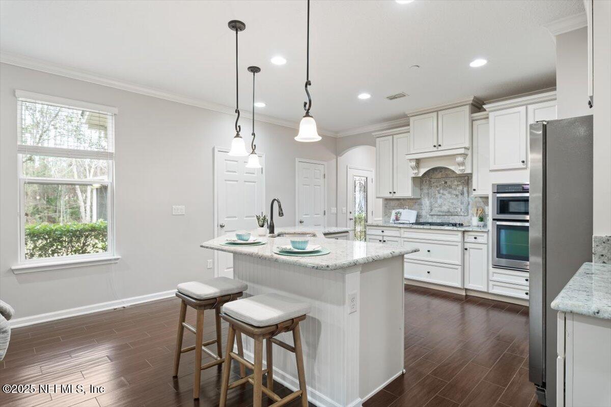 47 Myrtle Park Point Ponte Vedra, FL 32081 - Photo 11 of 58 a kitchen with stainless steel appliances kitchen island granite countertop a sink a stove a refrigerator and island with wooden floor