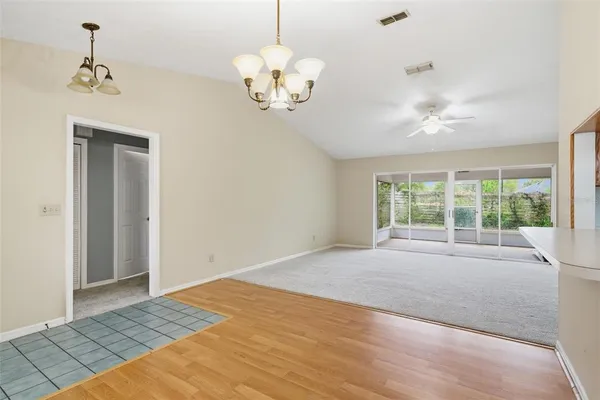 a view of an empty room with a chandelier fan and a rug