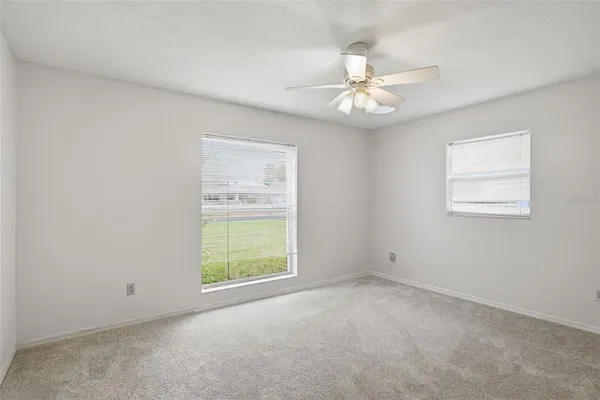 an empty room with windows and fan