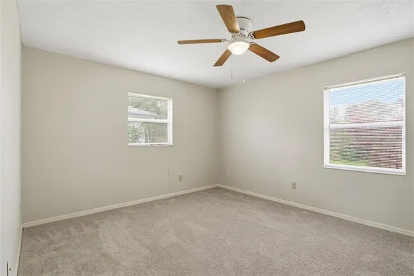 an empty room with a window and a fan