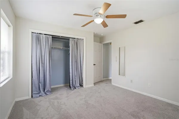 an empty room with closet and a ceiling fan
