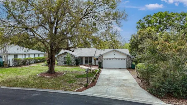 a front view of a house with a yard and large tree