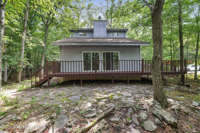 a view of a house with a wooden deck and a yard