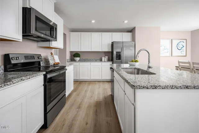 a kitchen with stainless steel appliances granite countertop a sink a stove a microwave a refrigerator and cabinets