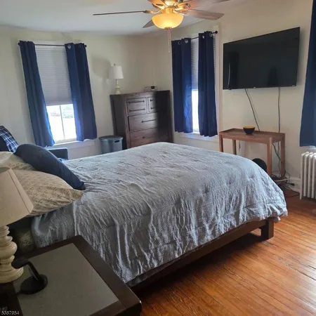 a bedroom with a bed tv and wooden floor