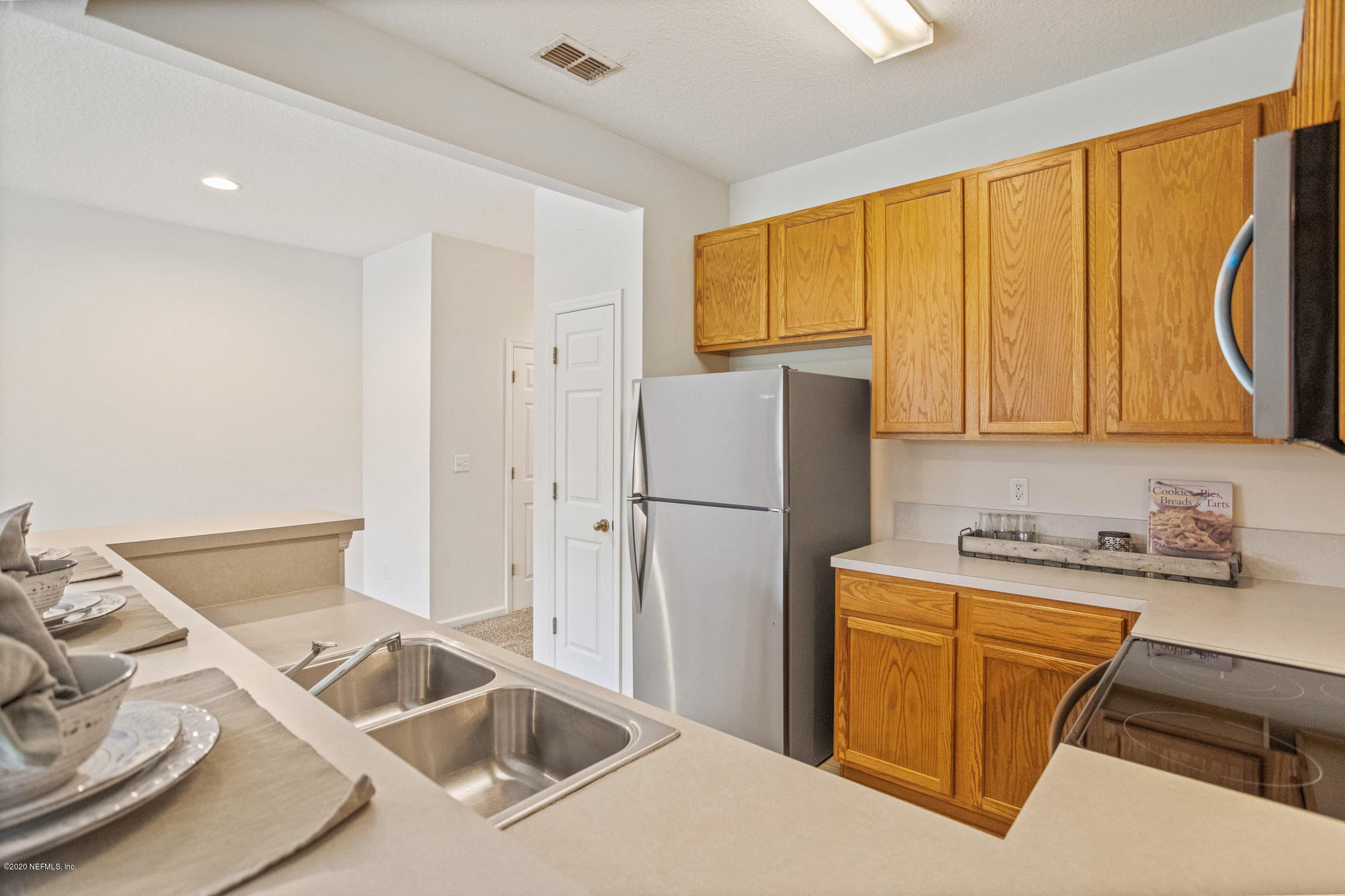 5784 Sandstone Way Jacksonville, FL 32258 - Photo 12 of 29 a kitchen with a sink a refrigerator and cabinets