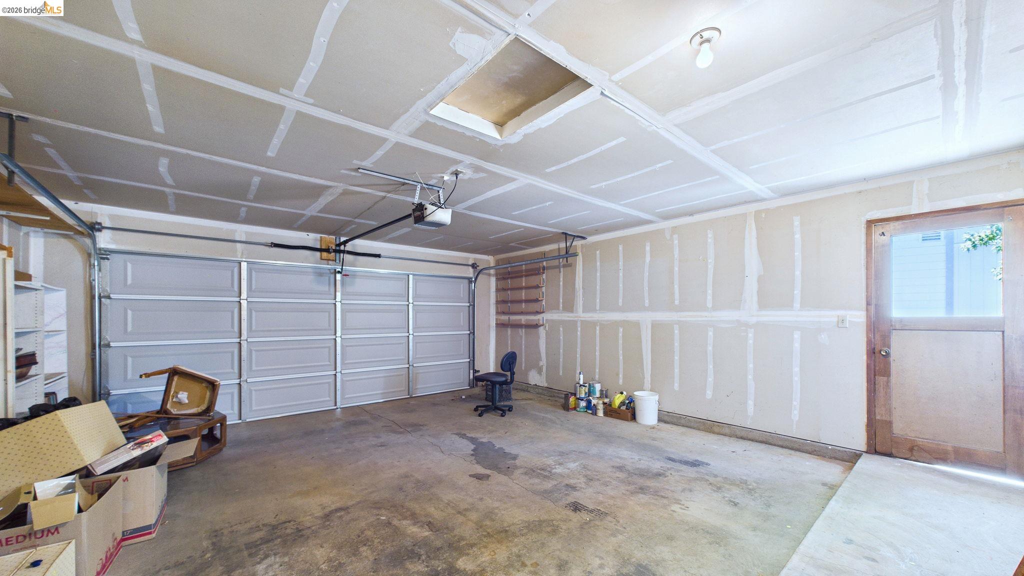 23686 Marble Quarry Road, Unit 72 Columbia, CA 95310 - Photo 35 of 35 Two overhead garage doors with automatic openers, exposed ceiling joists, concrete flooring, and a wood-paneled utility door with a glass insert