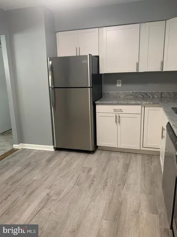 a kitchen with granite countertop white cabinets and refrigerator