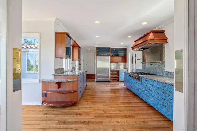 a large room with kitchen island granite countertop wooden floor stainless steel appliances and a window