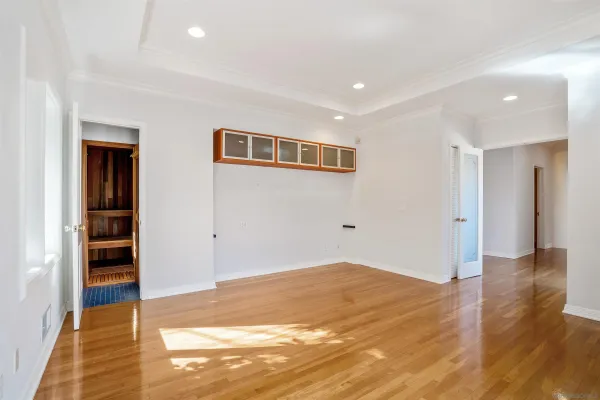 a view of an empty room with wooden floor and closet