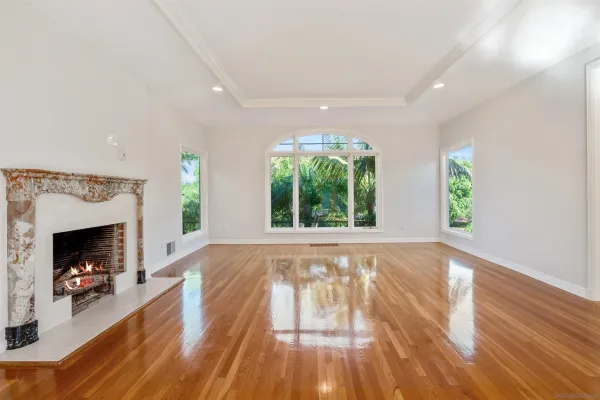 a view of an empty room with wooden floor fireplace and a window