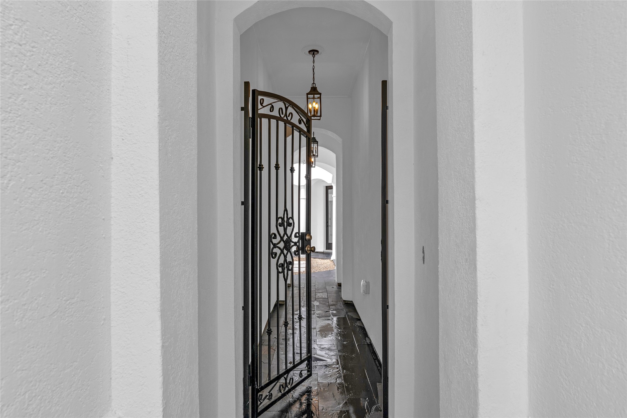 2031 Peppermill Road Houston, TX 77080 - Photo 3 of 48 The wrought iron gate opens to an arched corridor softly illuminated by hanging lanterns.
