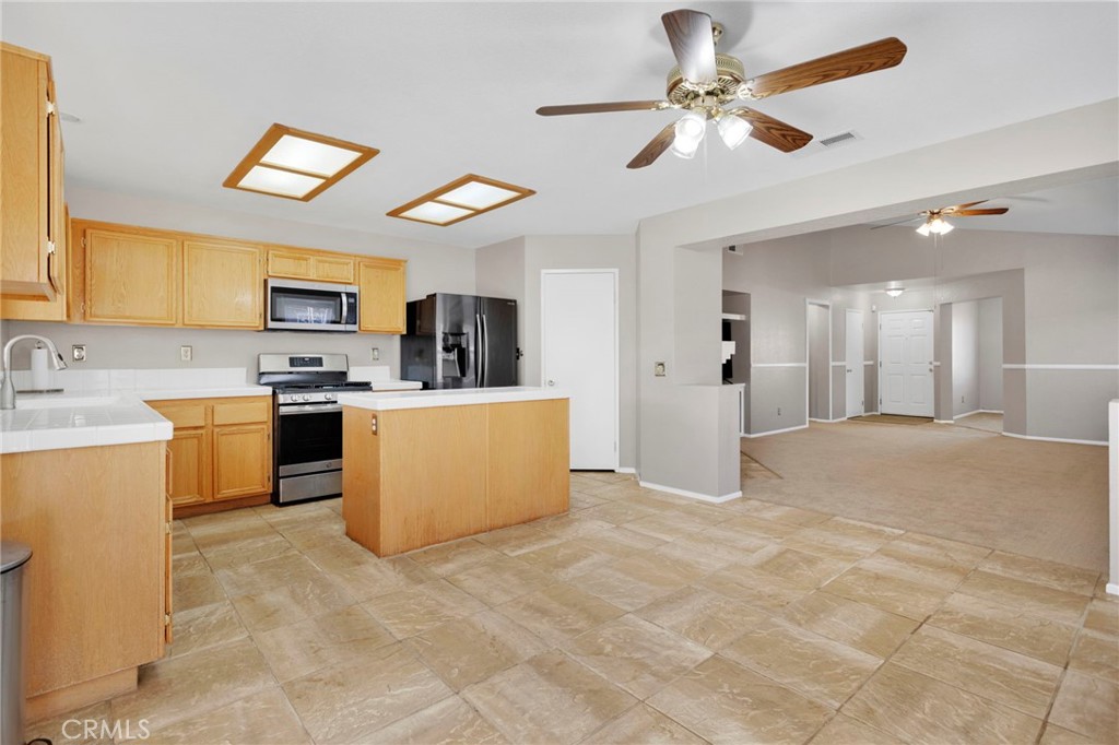 11979 Luna Road Victorville, CA 92392 - Photo 13 of 49 a view of a kitchen with kitchen island a sink stainless steel appliances and cabinets