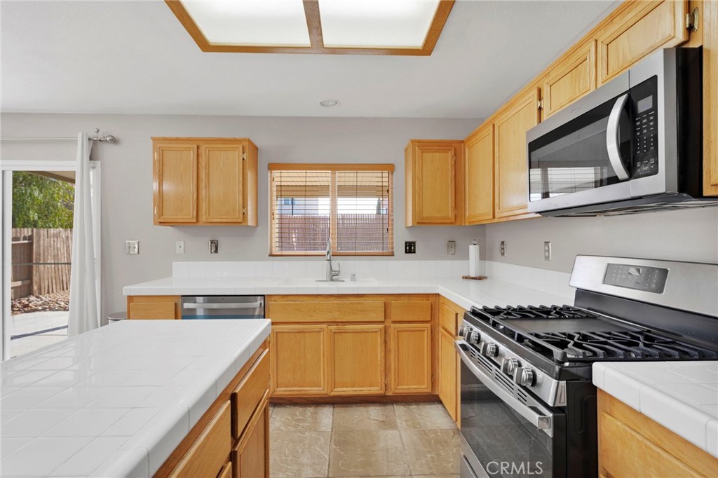 11979 Luna Road Victorville, CA 92392 - Photo 16 of 49 a kitchen with stainless steel appliances a stove cabinets and a sink