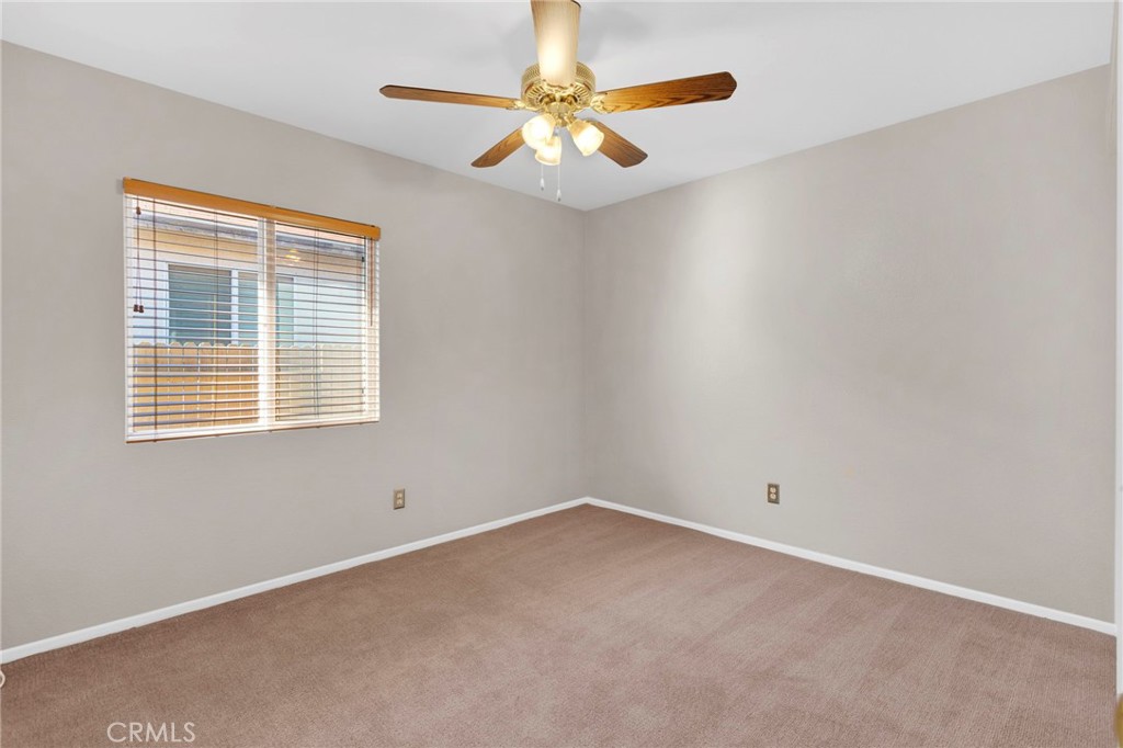 11979 Luna Road Victorville, CA 92392 - Photo 27 of 49 an empty room with windows and chandelier fan