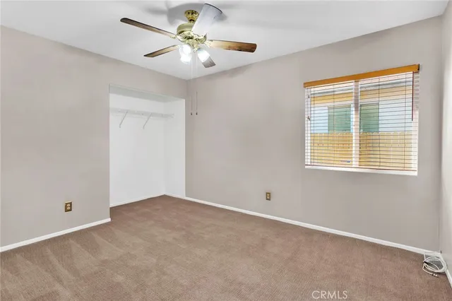 an empty room with closet and a chandelier fan