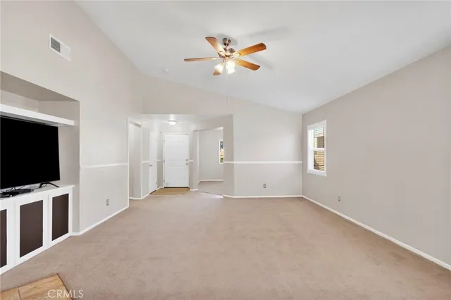 a view of a livingroom with a fireplace a ceiling fan and a window