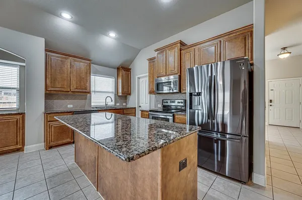 a kitchen with stainless steel appliances granite countertop a refrigerator a sink and a stove