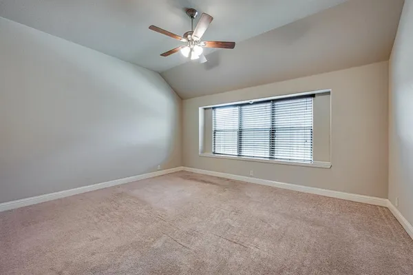 an empty room with chandelier fan and windows