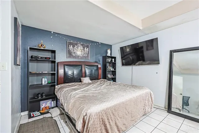 a bedroom with a bed and a flat tv screen on dresser