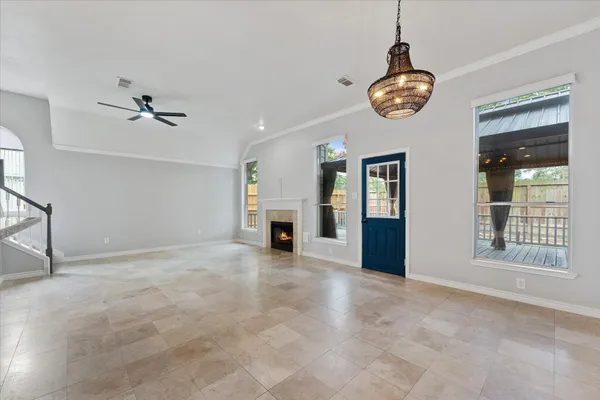 a view of an empty room with chandelier fan and wooden floor