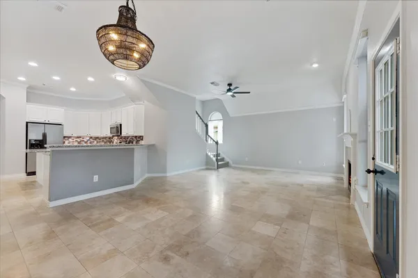 a view of an empty room with wooden floor and a ceiling fan