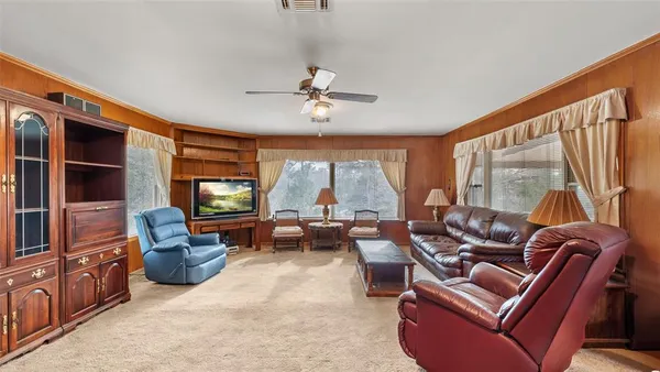 a living room with furniture a flat screen tv and large window