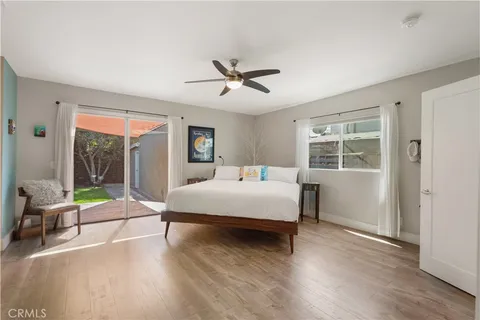 a bedroom with a bed lamp and a large window with wooden floor