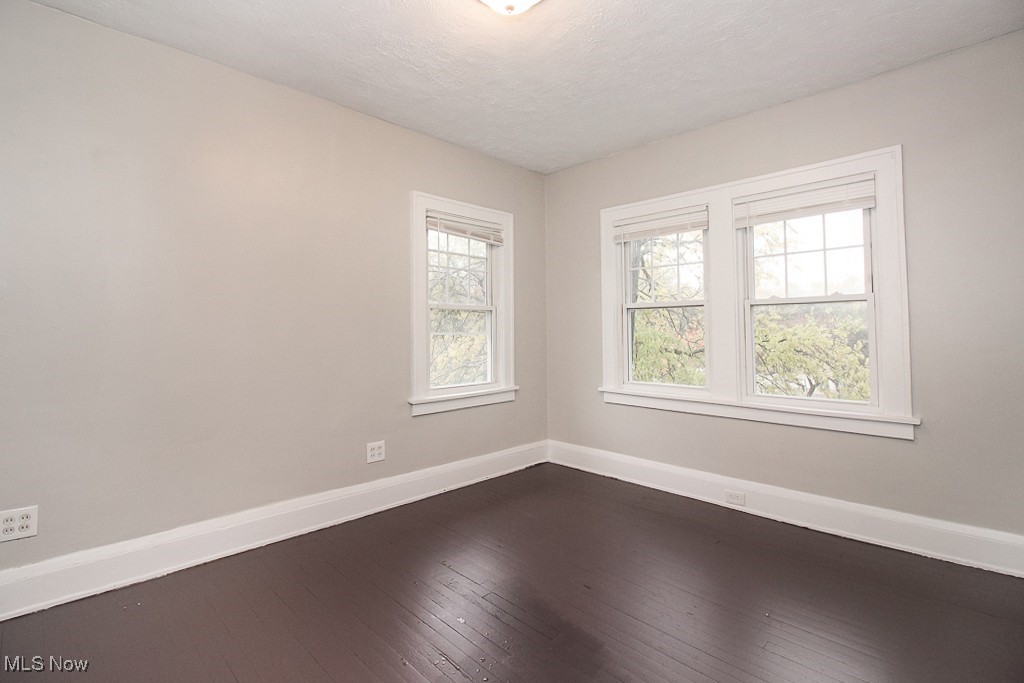 3085 Somerton Road Cleveland, OH 44118 - Photo 12 of 16 Empty room featuring dark wood-style floors, baseboards, and a textured ceiling