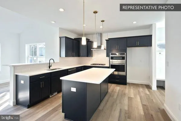 a kitchen with stainless steel appliances granite countertop a sink a stove a refrigerator and a oven with wooden floor