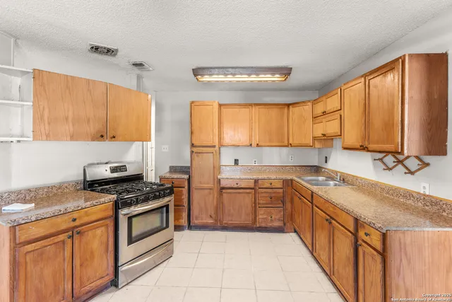 a kitchen with stainless steel appliances granite countertop wooden cabinets a stove a sink and a window