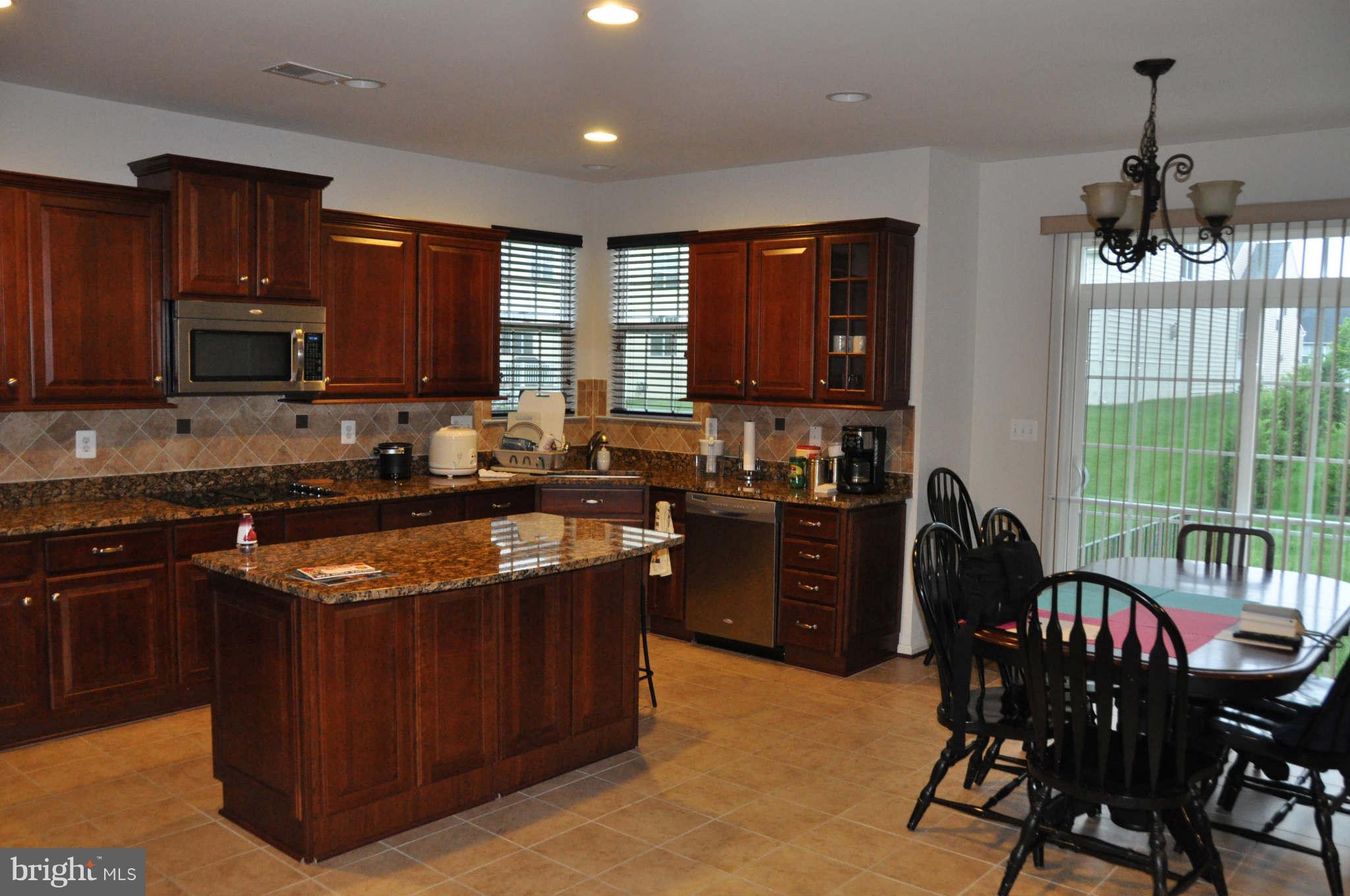 6627 Pebble Brooke Road Baltimore, MD 21209 - Photo 3 of 12 a kitchen with stainless steel appliances granite countertop a stove a sink dishwasher a microwave oven and a dining table with wooden cabinet